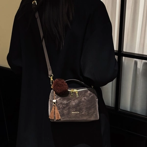 Détail du sac polochon en velours gris foncé avec breloques bordeaux et zips dorés