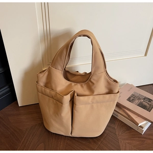 Detail shot of beige nylon tote bag with multiple front pockets for daily commute