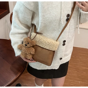 Detalle de bolso bandolera de ante con ribete de pelo sintético y colgante de osito