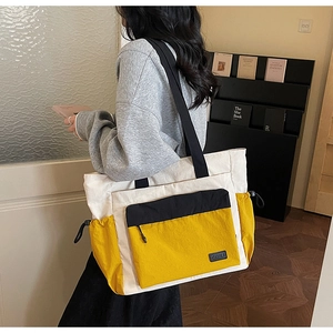 Detail of multi-pocket canvas tote bag with drawstring sides and stylish color block design