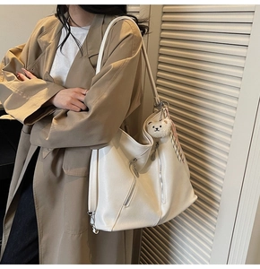 Détail du cabas en cuir blanc avec fermetures éclair argentées et breloque ours en peluche