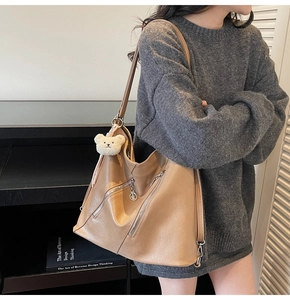 Détail du sac hobo kaki avec fermetures éclair décoratives et breloque ours en peluche
