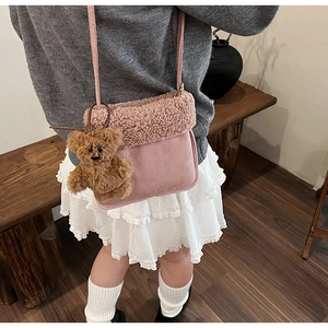 Detalle del bolso bandolera de ante rosa con ribete de forro polar y colgante de osito