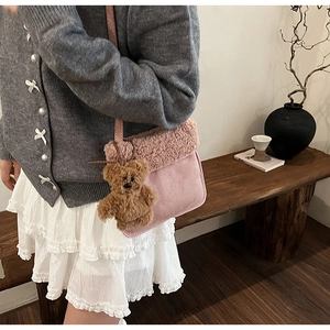 Detalle de bolso bandolera de felpa rosa con adorable colgante de oso marrón