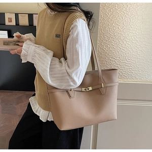 Detail of elegant large tote bag with lychee grain leather and metal clasp decoration