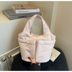 Detail of light pink quilted tote bag with two front pockets in a cozy home setting
