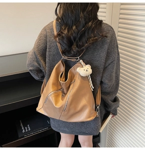 Détail du sac Hobo kaki avec fermetures éclair diagonales et breloque ours en peluche