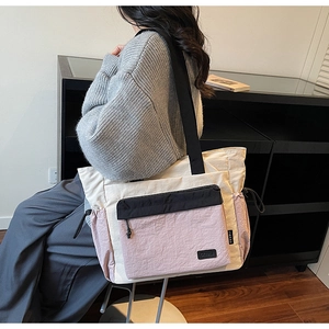 Detail view of large color-block tote bag with drawstring pocket and black wide strap