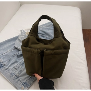 Detail of olive green nylon tote bag featuring two large front pockets and durable fabric