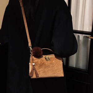 Détail du sac bandoulière en daim vintage avec pompon décoratif et breloque en peluche