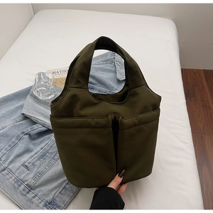 Detail of army green nylon handbag with front pockets on white linen background