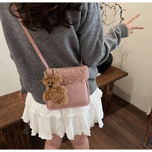 Bolso bandolera de felpa rosa con colgante de oso y detalles de patchwork en la modelo