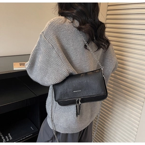 Détail du sac bandoulière noir en cuir grainé avec chaîne argentée et pompons