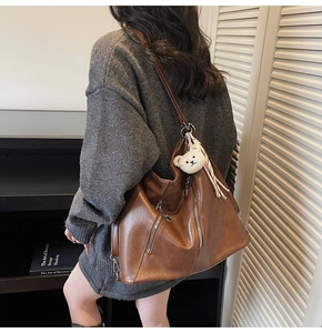 Sac cabas vintage en similicuir marron avec pendentif ours blanc porté par un modèle