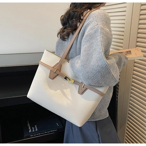 Detail of off-white lychee texture tote bag with brown straps and metal buckle closure