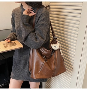 Détail d'un sac cabas vintage marron avec fermetures éclair et porte-clé ours blanc