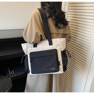 Side view of model wearing a contrast color tote bag with black trim and zipper pocket