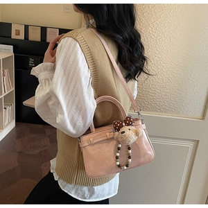 Detailansicht der rosa Ledertasche mit Teddy-Anhänger an einem Model in gemütlicher Szene
