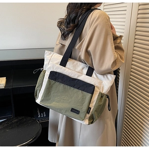 Detail of color-block nylon tote bag showing drawstring side pockets and fabric texture