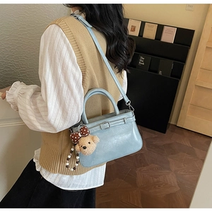 Vue détaillée du sac à main bleu clair avec breloque ours brun sur une tenue élégante