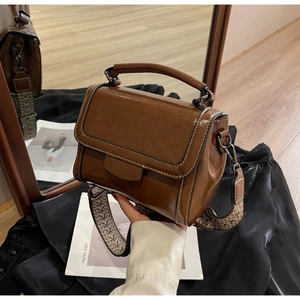 Detail der vintage-braunen quadratischen Handtasche mit Öl-Wachs-Textur und Webriemen