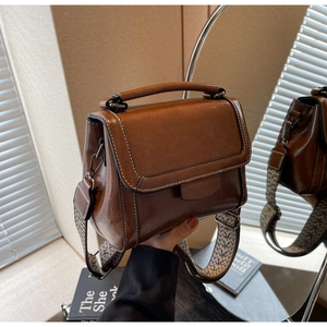 Nahaufnahme braune Vintage PU-Handtasche mit weißen Nähten und gewebtem Schultergurt