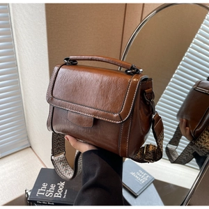 Nahaufnahme der braunen Vintage-Lederhandtasche mit gewebtem Riemen und Metallbeschlägen