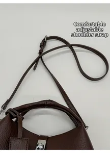 Detail of adjustable shoulder strap and silver clasp on dark brown leather bucket bag