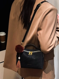 Sac à bandoulière en cuir noir avec fermetures éclair dorées et pompon décoratif