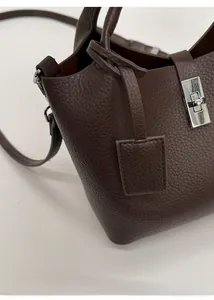Detail of premium lychee texture leather on dark brown bucket bag with silver metal lock