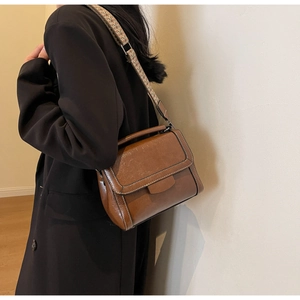 Nahaufnahme der braunen PU-Ledertasche mit weißen Nähten und geometrischem Tragegurt