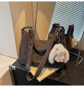 Detalle de bolso bandolera marrón oscuro con un tierno colgante de conejo de peluche