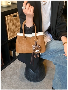 Detail of brown faux leather tote with white faux fur trim and leopard plush charm