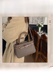 Détail du sac seau marron foncé à texture litchi avec boucle en métal et bandoulière