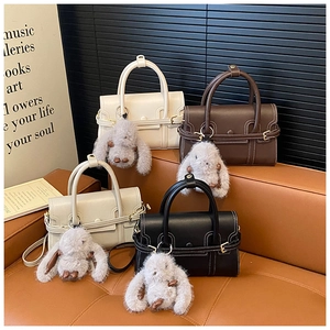 Detail of four colorful square handbags on a leather sofa with cute bunny charms