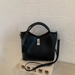Detail of black lychee grain leather bucket bag with silver twist lock and round handle