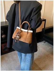 Close-up of brown suede handbag with white faux fur trim and cute plush monster charm