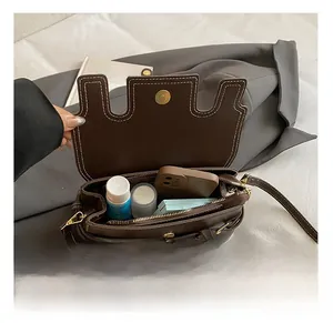 Detail view of the brown crossbody bag interior with white stitching and gold hardware