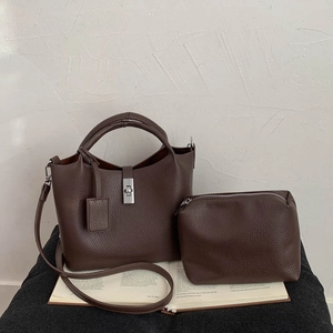 Close-up of brown lychee grain leather bucket bag with silver metal lock and inner pouch