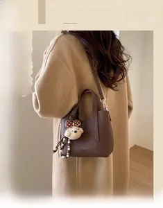 Detail of dark brown pebble leather bucket bag featuring a cute teddy bear charm pendant