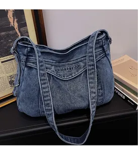Detail of blue denim tote bag with SUBELETING embroidery and adjustable shoulder strap
