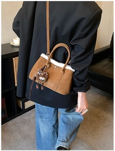 Detailed view of brown crossbody bag with white faux fur trim and cute monster charm