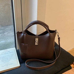 Detail of dark brown lychee grain leather bucket bag featuring silver buckle and strap