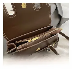 Detail of brown leather handbag interior with gold hardware and white contrast stitching