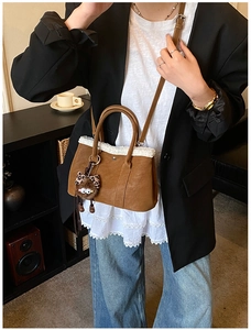 Brown leather crossbody bag featuring faux fur trim and cute plush doll pendant detail