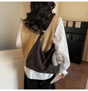 Detalle del bolso hobo de media luna marrón oscuro con un adorno de peluche de conejo