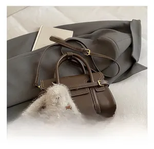 Detailed shot of a brown leather handbag with white stitching and a plush rabbit charm