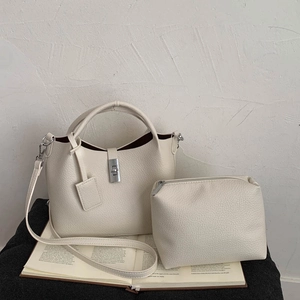 Detail of cream pebbled leather bucket bag set with silver metal clasp and inner pouch
