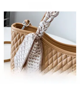 Detalle del bolso acolchado marrón con un pañuelo decorativo de seda en el asa superior