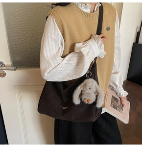 Detalle de bolso bandolera vintage marrón oscuro con un dije de conejo de peluche